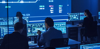 Sala de control moderna con personas frente a computadoras y pantallas iluminadas en azul que muestran datos complejos.